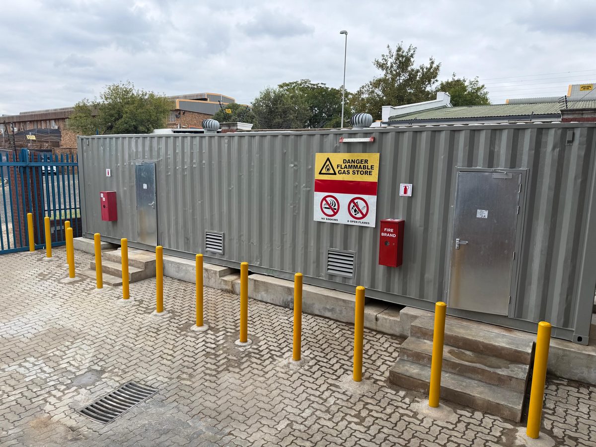 Flammable gas storage container installation with safety bollards and signage