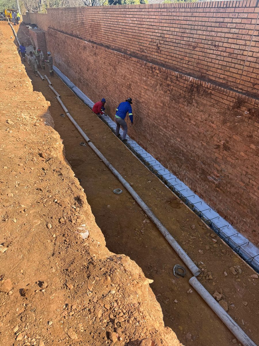 Reinforced concrete footing and rebar along a brick boundary wall, Gauteng
